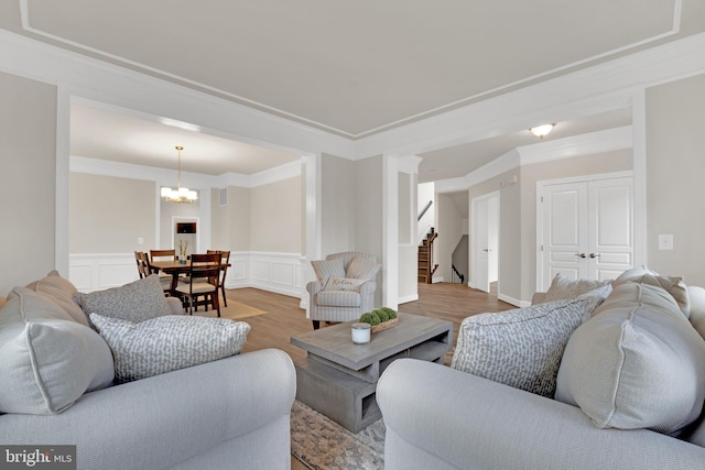 living room with ornamental molding, a chandelier, and wood-type flooring