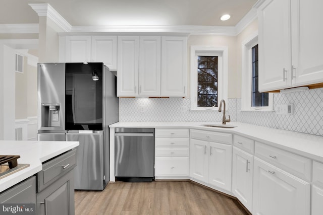 kitchen with sink, white cabinets, crown molding, and appliances with stainless steel finishes