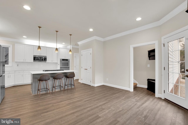 kitchen featuring hanging light fixtures, a center island, stainless steel appliances, backsplash, and white cabinets