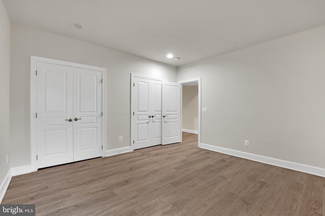 unfurnished bedroom with two closets and light hardwood / wood-style floors