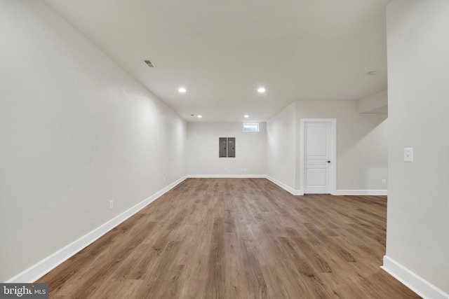 unfurnished room with electric panel and light hardwood / wood-style flooring