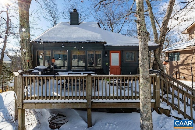 snow covered rear of property with a wooden deck