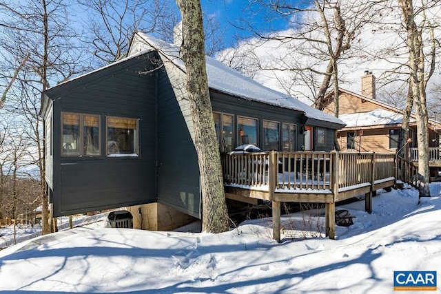 snow covered back of property featuring a wooden deck