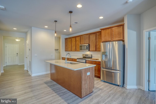 kitchen featuring light hardwood / wood-style floors, an island with sink, stainless steel appliances, hanging light fixtures, and sink