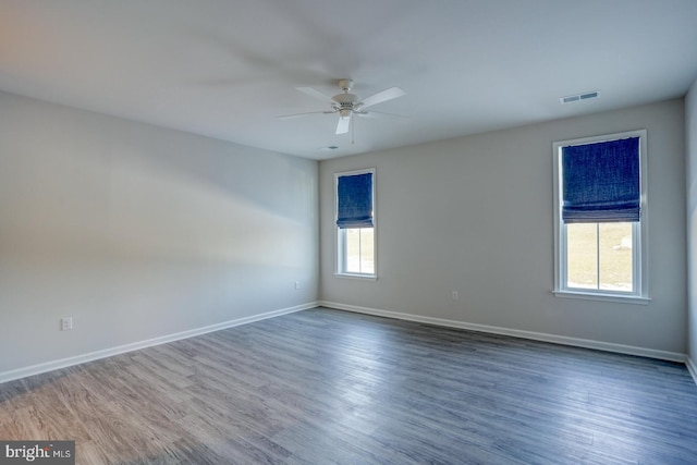 spare room with ceiling fan, a healthy amount of sunlight, and dark wood-type flooring