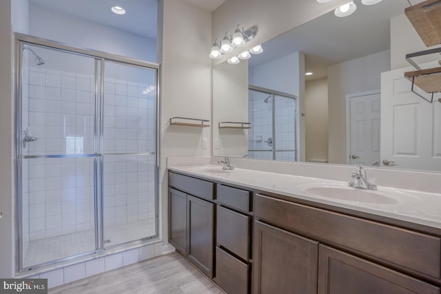 bathroom featuring a shower with shower door and vanity