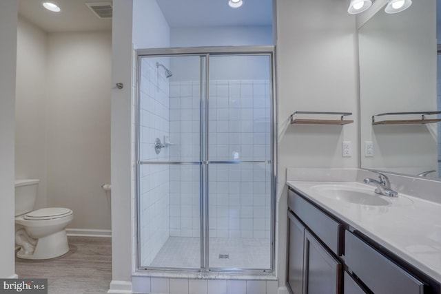 bathroom featuring hardwood / wood-style floors, toilet, a shower with door, and vanity