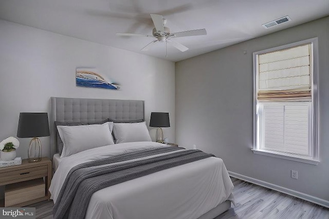 bedroom featuring ceiling fan, multiple windows, and light hardwood / wood-style flooring