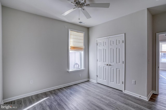 unfurnished bedroom with ceiling fan, wood-type flooring, and a closet