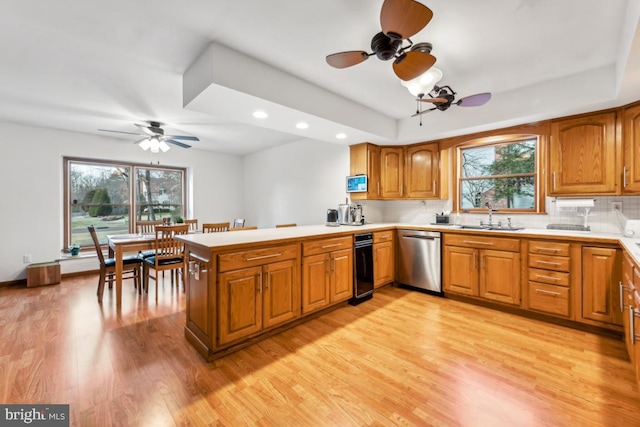 kitchen featuring dishwasher, light hardwood / wood-style floors, kitchen peninsula, decorative backsplash, and a wealth of natural light