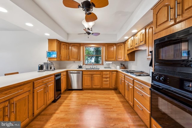 kitchen featuring sink, decorative backsplash, black appliances, and light hardwood / wood-style flooring