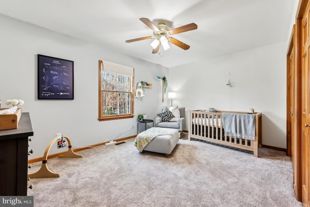 bedroom featuring ceiling fan, light colored carpet, and a nursery area