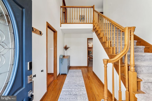 foyer with a towering ceiling and light wood-type flooring