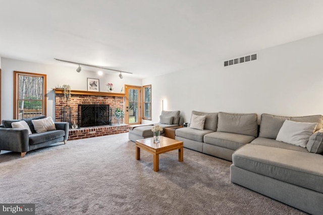 carpeted living room featuring track lighting and a brick fireplace