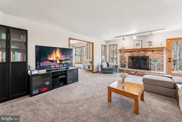 living room with light colored carpet, track lighting, a brick fireplace, and plenty of natural light