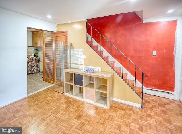 stairway with baseboard heating and parquet floors