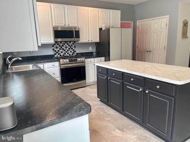 kitchen featuring stainless steel appliances, white cabinetry, a kitchen island, and sink