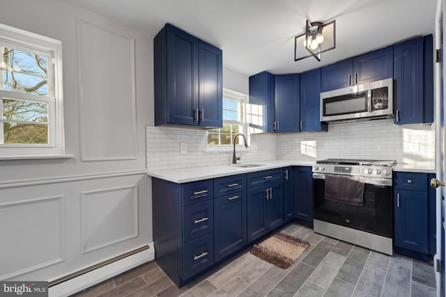 kitchen featuring appliances with stainless steel finishes, a baseboard heating unit, sink, blue cabinets, and backsplash