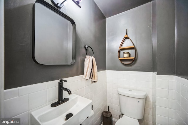 bathroom with tile walls, toilet, and sink