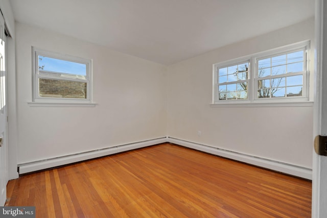 unfurnished room with a baseboard heating unit and hardwood / wood-style flooring