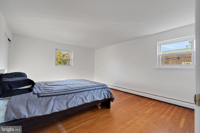 bedroom with a baseboard heating unit and hardwood / wood-style flooring