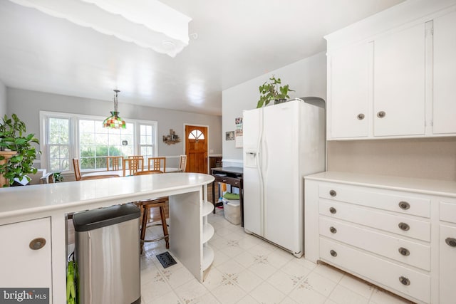 kitchen with white cabinetry, white refrigerator with ice dispenser, and decorative light fixtures