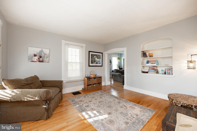 living room featuring built in features and wood-type flooring