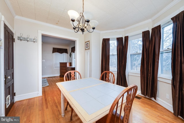 dining space featuring ornamental molding, an inviting chandelier, and light hardwood / wood-style flooring