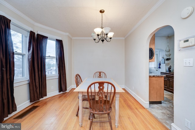 dining room with ornamental molding, light hardwood / wood-style floors, and a notable chandelier