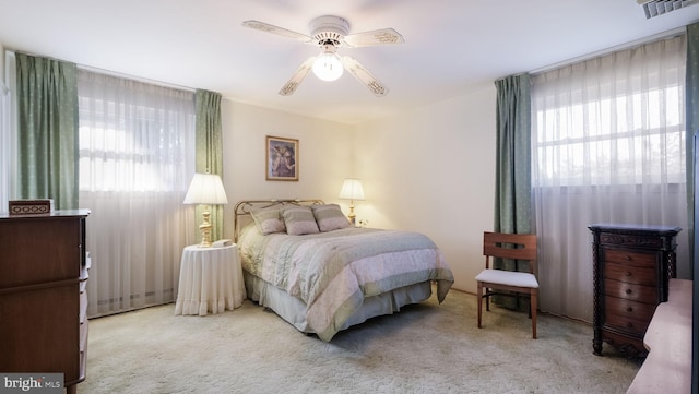 carpeted bedroom featuring multiple windows and ceiling fan