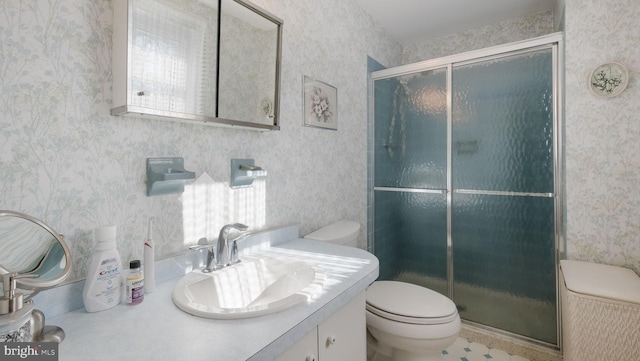 bathroom featuring toilet, a shower with door, and vanity