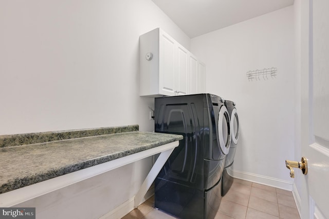 laundry room with cabinets, washing machine and dryer, and light tile patterned floors