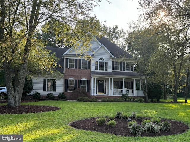 colonial-style house featuring a front yard and covered porch