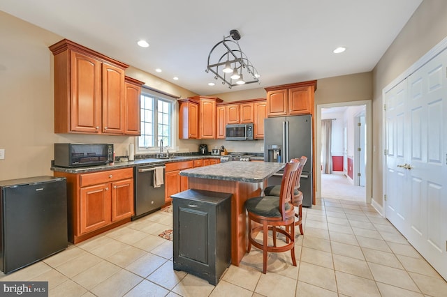 kitchen featuring a kitchen bar, hanging light fixtures, light tile patterned floors, appliances with stainless steel finishes, and a kitchen island