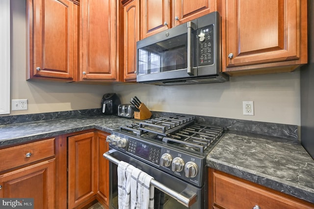 kitchen with stainless steel appliances and dark stone counters