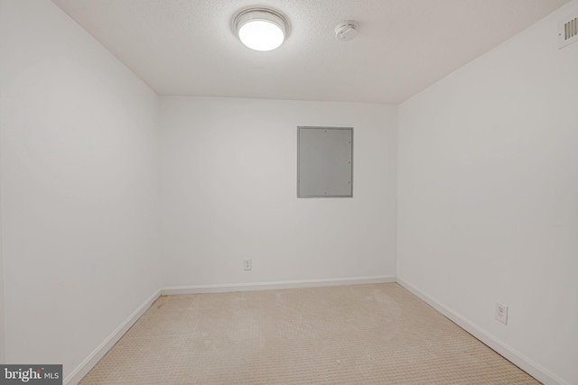 carpeted empty room with a textured ceiling and electric panel