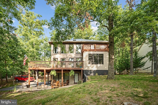 rear view of property featuring a wooden deck and a lawn