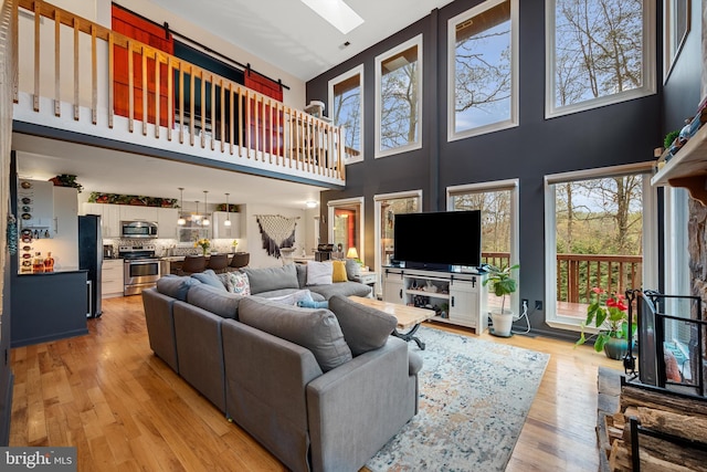 living room with a towering ceiling, light hardwood / wood-style floors, and a skylight