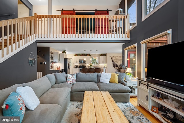 living room featuring a towering ceiling and light wood-type flooring