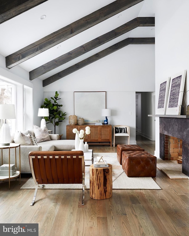 living room featuring light hardwood / wood-style flooring, beam ceiling, a fireplace, and high vaulted ceiling