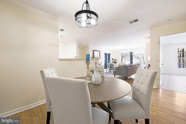 dining space with hardwood / wood-style flooring, ornamental molding, and a chandelier