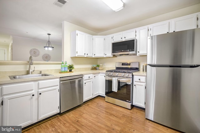 kitchen featuring pendant lighting, white cabinetry, sink, light hardwood / wood-style floors, and stainless steel appliances