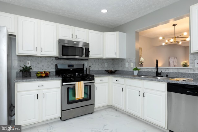 kitchen with a chandelier, stainless steel appliances, tasteful backsplash, white cabinetry, and sink