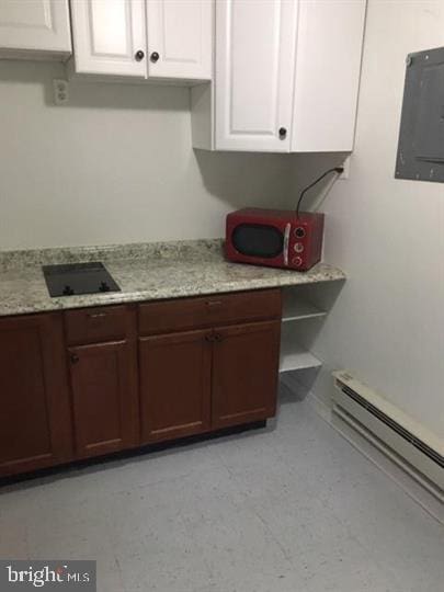 kitchen featuring electric panel, a baseboard heating unit, black electric stovetop, and white cabinetry