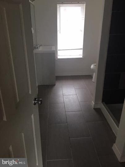 bathroom featuring toilet, tile patterned flooring, walk in shower, and sink