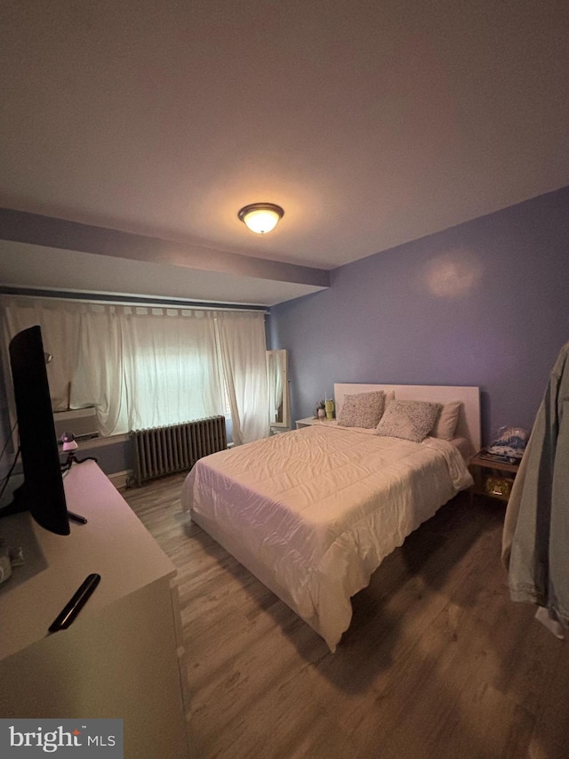 bedroom with radiator heating unit and wood finished floors