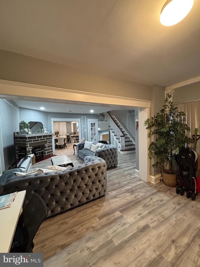 living area with baseboards, wood finished floors, and stairs