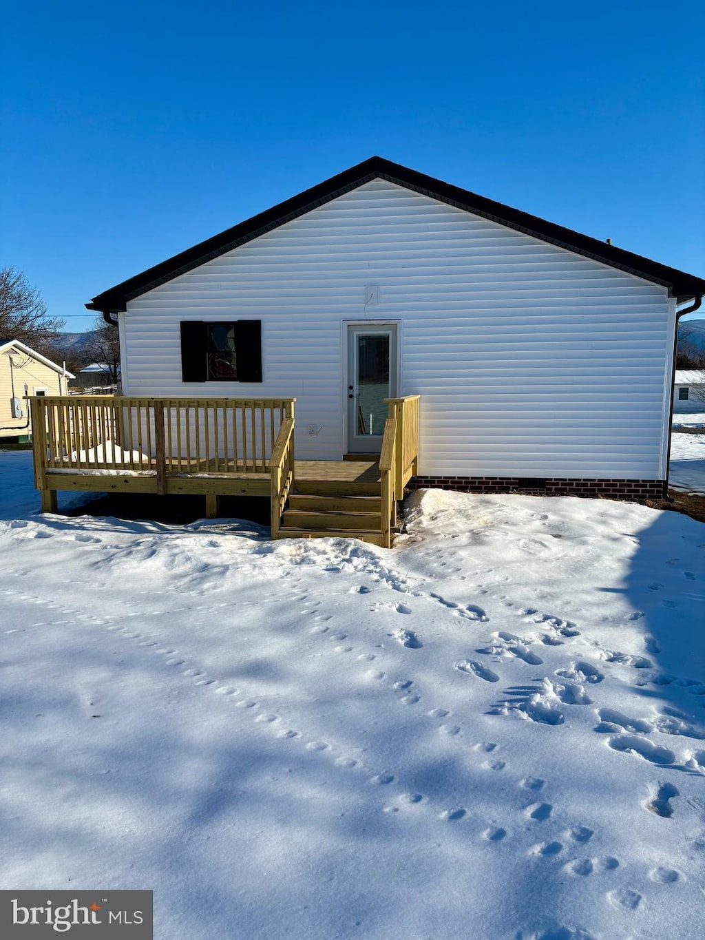 snow covered rear of property featuring a wooden deck