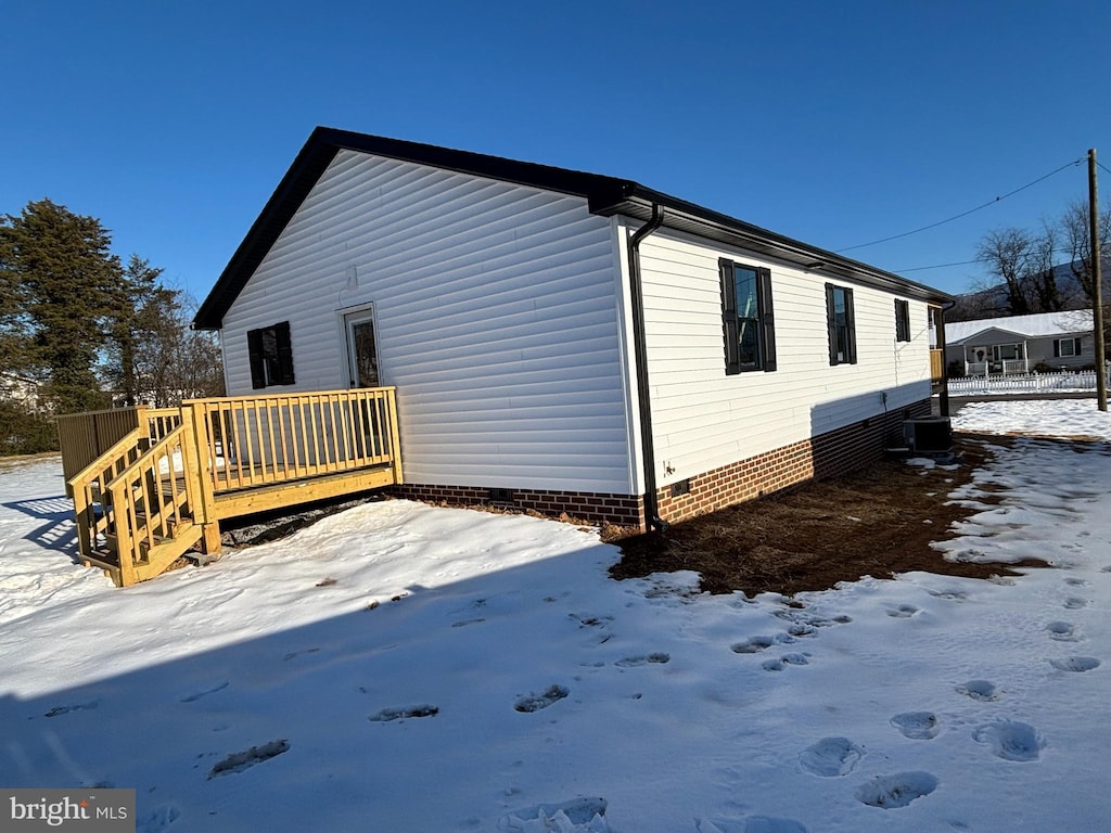 view of snow covered exterior featuring a wooden deck and central AC unit