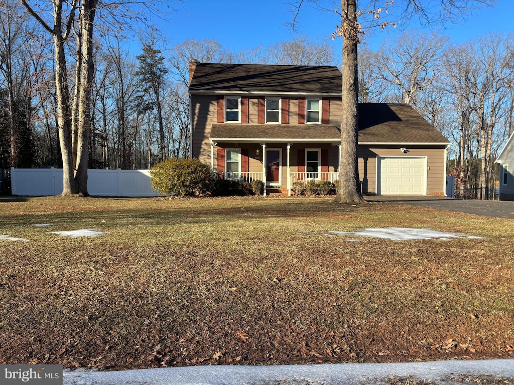 colonial inspired home featuring a front yard, a garage, and a porch